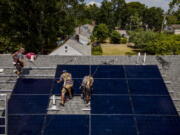 FILE - Employees of NY State Solar, a residential and commercial photovoltaic systems company, install an array of solar panels on a roof, Thursday, Aug. 11, 2022, in the Long Island hamlet of Massapequa, N.Y.  Americans are less concerned now about how climate change might impact them personally -- and about how their personal choices affect the climate than they were three years ago, according to a according to a June poll from The Associated Press-NORC Center for Public Affairs Research.