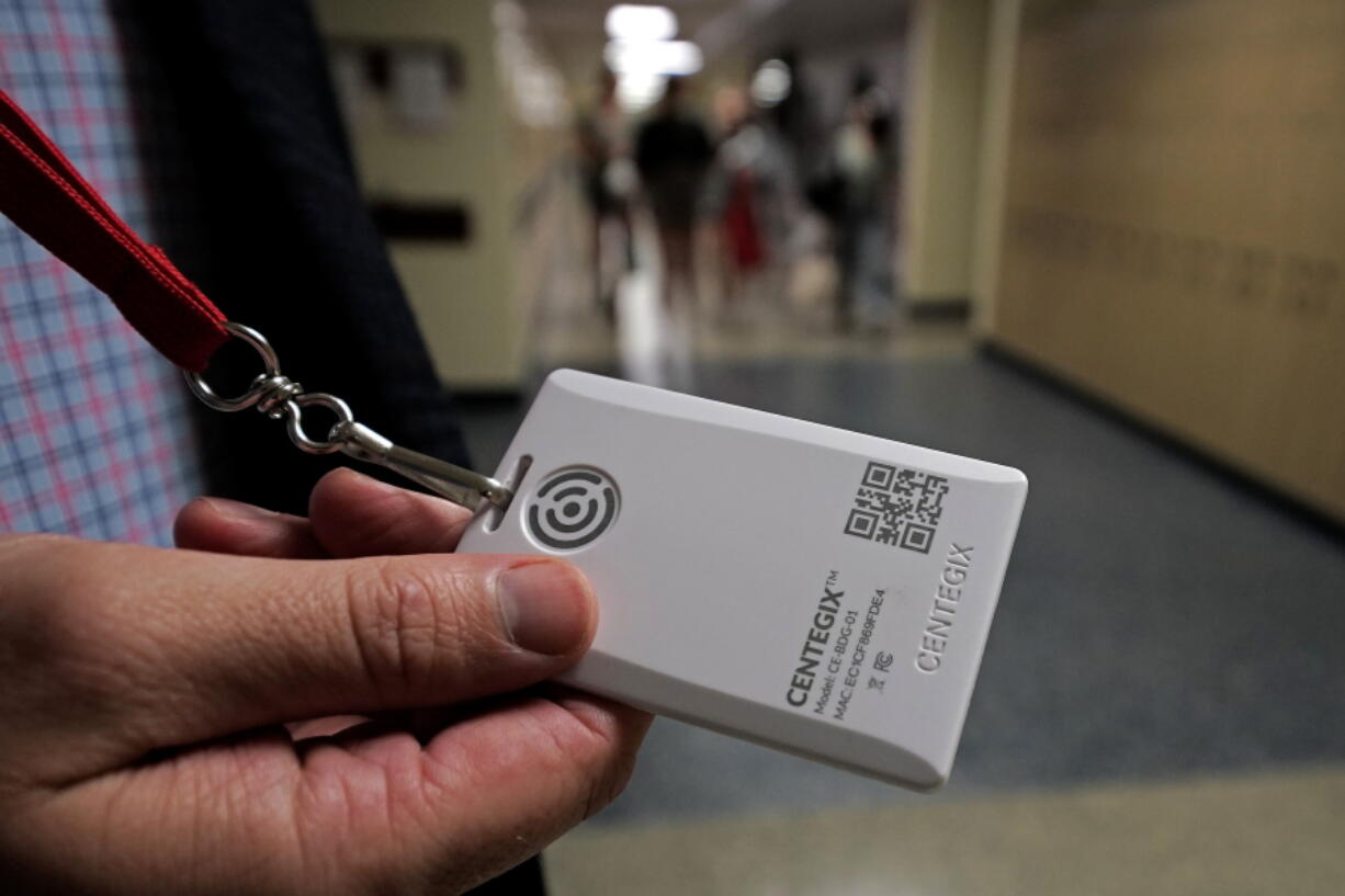 Brent Kiger, Olathe Public Schools' director of safety service, displays a panic-alert button while students at Olathe South High School rush between classes Friday, in Olathe, Kan.