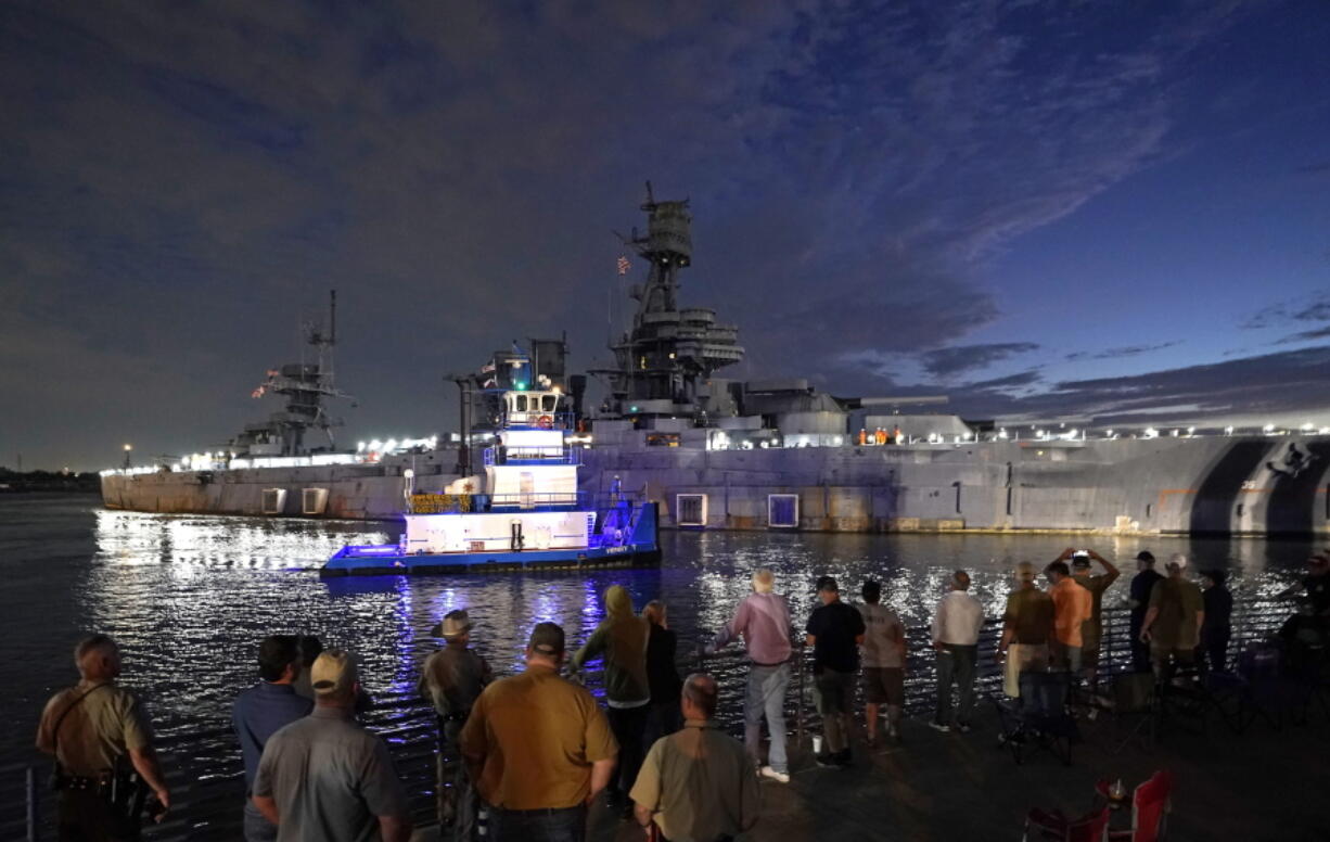 People watch as the USS Texas is moved from the dock Wednesday, Aug. 31, 2022, in La Porte, Texas. The vessel, which was commissioned in 1914 and served in both World War I and World War II, is being towed down the Houston Ship Channel to a dry dock in Galveston where it will undergo an extensive $35 million repair. (AP Photo/David J.