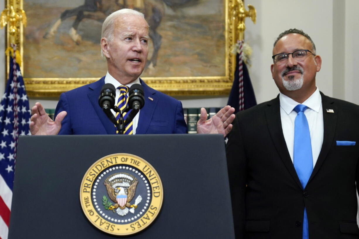 FILE -- President Joe Biden speaks about student loan debt forgiveness in the Roosevelt Room of the White House, Aug. 24, 2022, in Washington. Education Secretary Miguel Cardona listens at right. Many have cheered President Joe Biden's proposal to provide student loan forgiveness to millions of Americans as a significant step toward addressing the nation's racial wealth gap and other inequities facing borrowers of color.