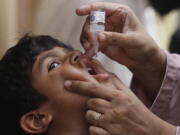 FILE - A health worker gives a polio vaccine to a child in Karachi, Pakistan, May 23, 2022. British health authorities on Wednesday, Aug. 10 say they will offer a polio booster dose to children aged 1 to 9 in London, after finding evidence the virus has been spreading in multiple regions of the capital, despite not confirming any cases of the paralytic disease in people.