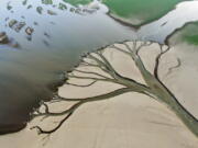 In this aerial photo released by China's Xinhua News Agency, water flows through chanels in the lake bed of Poyang Lake, China's largest freshwater lake, in eastern China's Jiangxi Province, Monday, Aug. 22, 2022. With China's biggest freshwater lake reduced to just 25% of its usual size by drought, work crews are digging trenches to keep water flowing to irrigate crops.