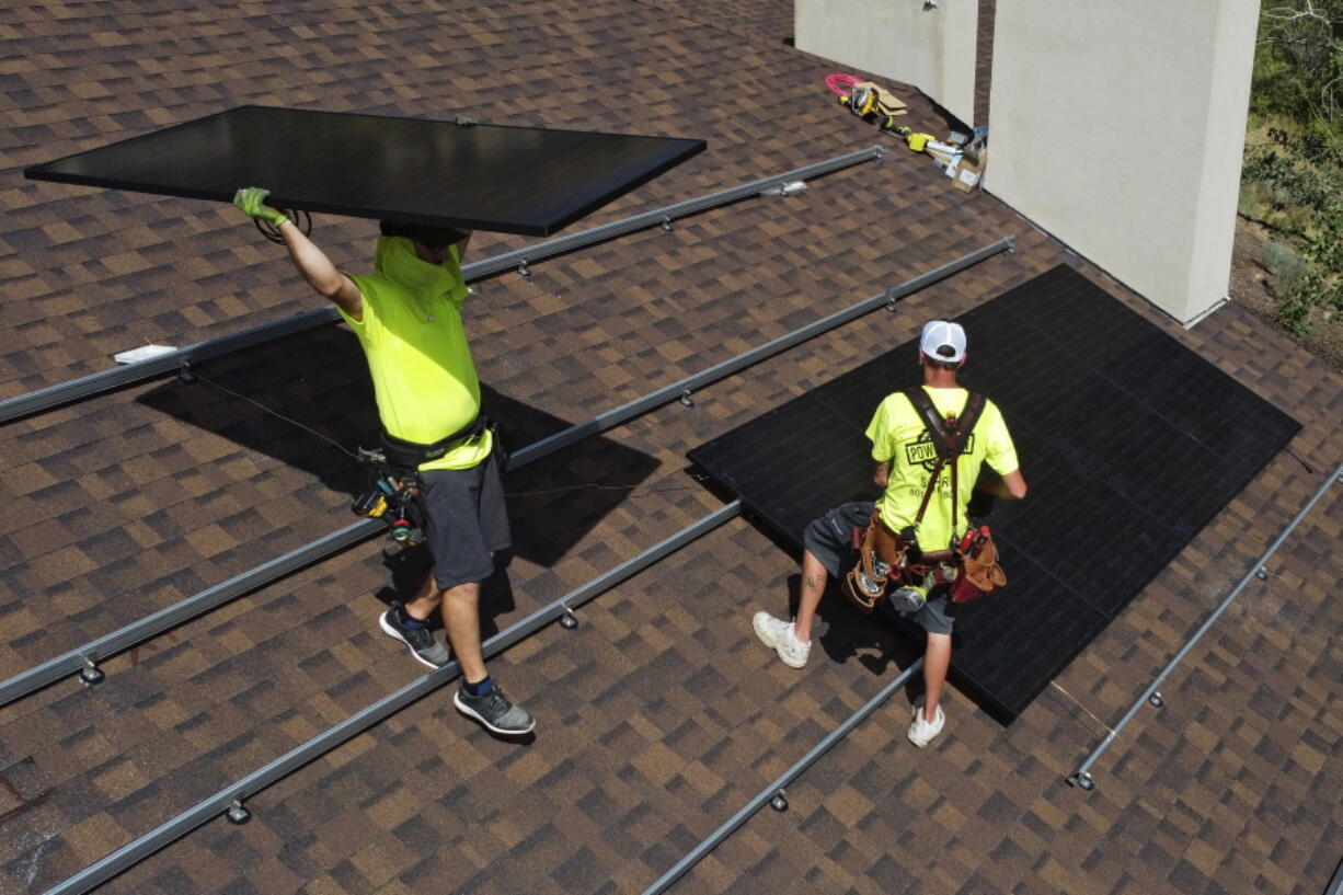 Workman with Power Shift Solar put solar panels on a house Wednesday, Aug. 10, 2022, in Salt Lake City. Congress is poised to pass a transformative climate change bill on Friday, Aug. 12. The crux of the long-delayed bill is to use incentives to accelerate the expansion of clean energy such as wind and solar power, speeding the transition away from the oil, coal and gas that largely cause climate change.