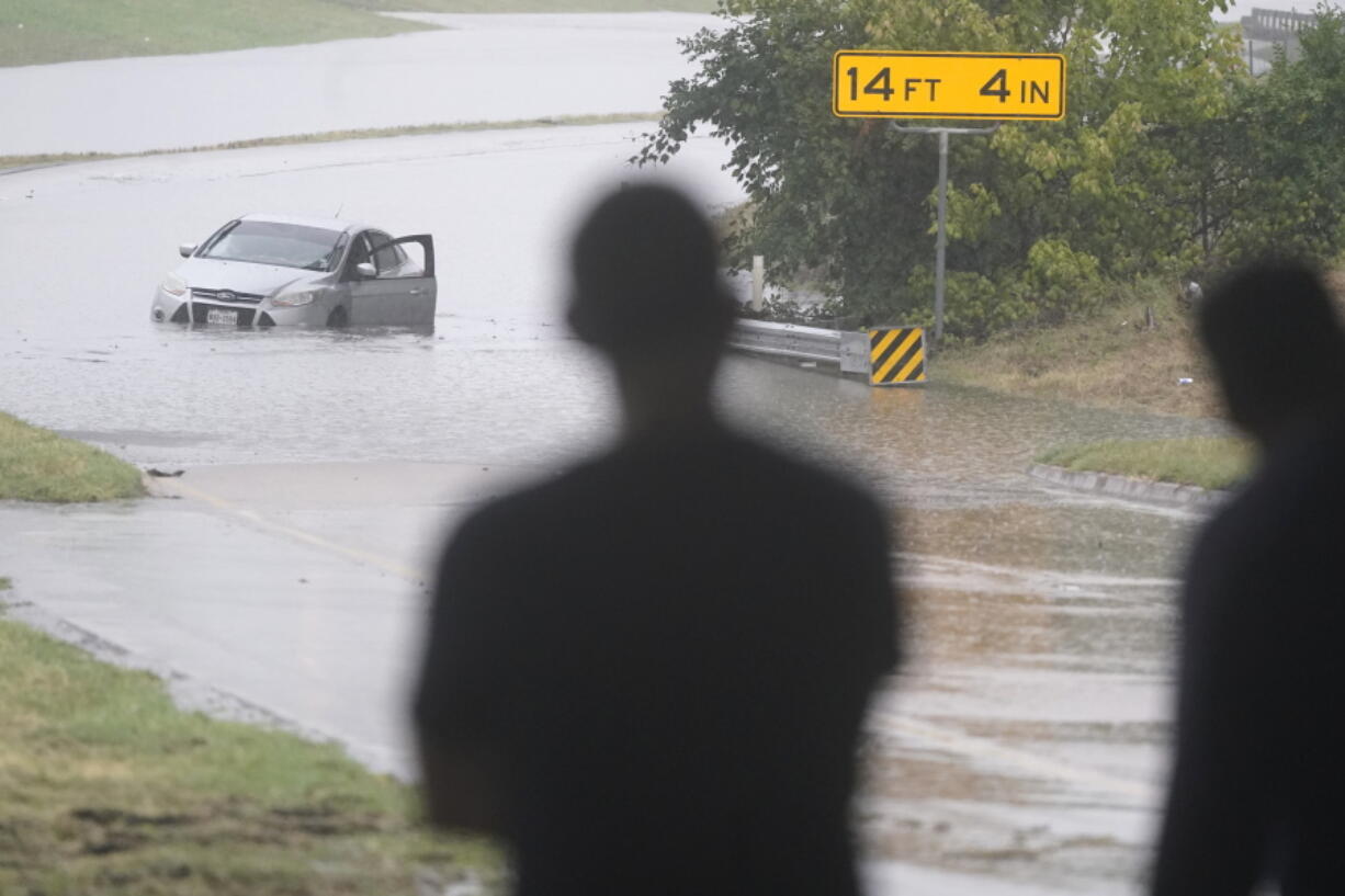 A swamped car sits in flood waters covering a closed highway in Dallas, Monday, Aug. 22, 2022.