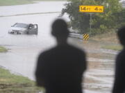 A swamped car sits in flood waters covering a closed highway in Dallas, Monday, Aug. 22, 2022.