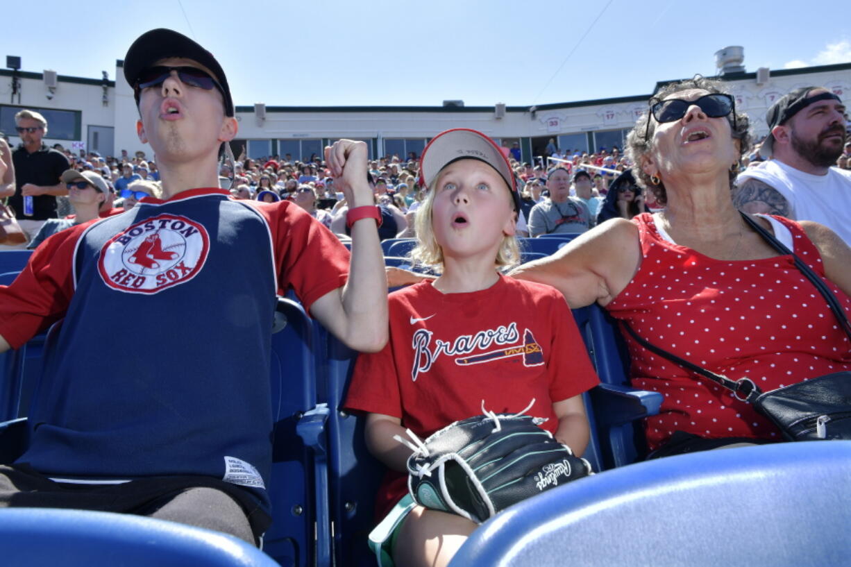 From left, Wyatt Smith, 17, of Waterville, Maine, Tessa Dutil, 9, of Sidney, Maine, and their grandmother Anne Smith, of Watervillle, Maine, react to a hit during the game between the Portland Sea Dogs and the Hartford Yard Goats, Sunday, August 28, 2022, at Hadlock Field in Portland, Maine. Across the northeastern U.S., outdoor businesses are profiting from the unusually dry weather.