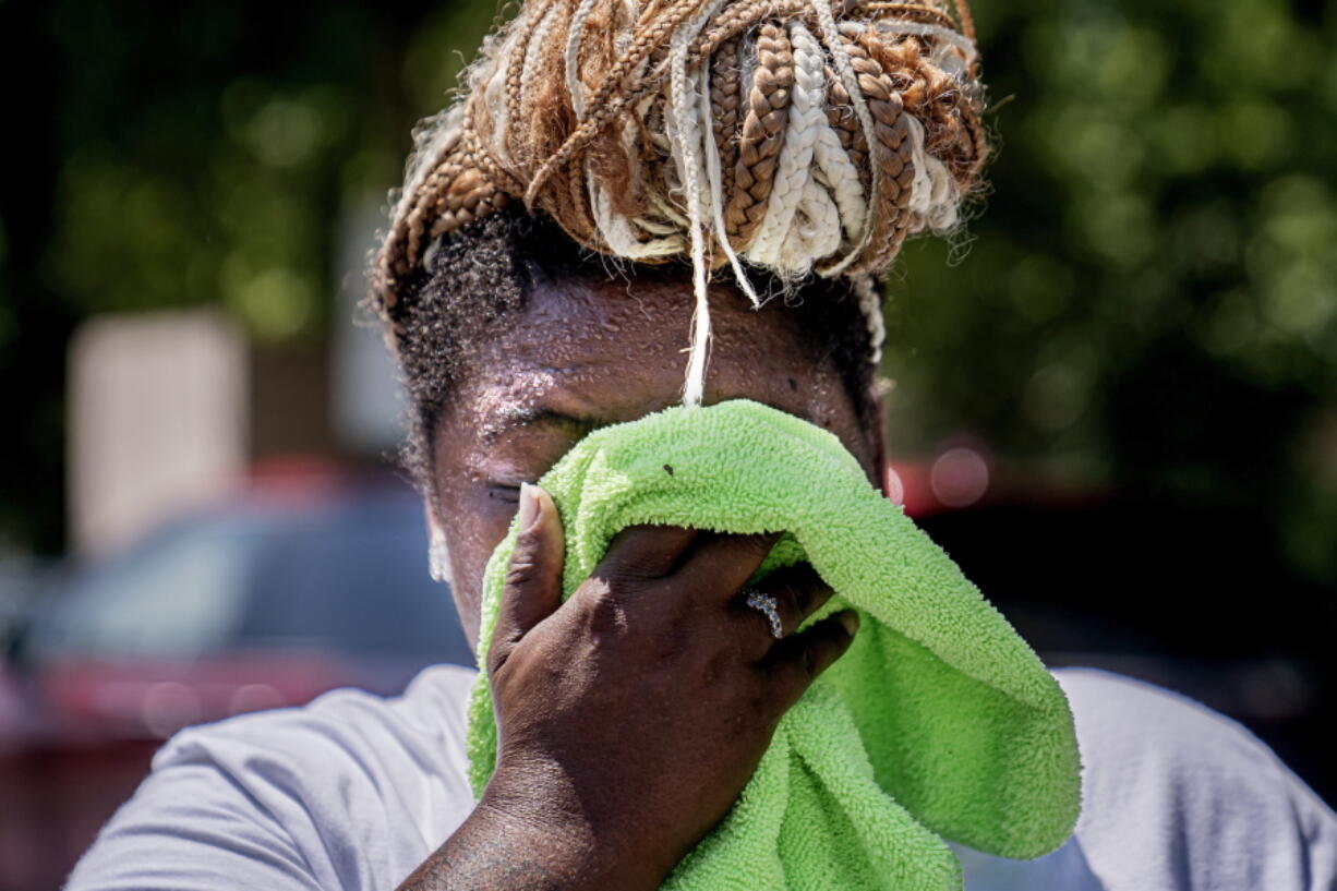 FILE - Nicole Brown wipes sweat from her face while setting up her beverage stand near the National Mall on July 22, 2022, in Washington. What's considered officially "dangerous heat" in coming decades will likely hit much of the world at least three times more often as climate change worsens, according to a new study.