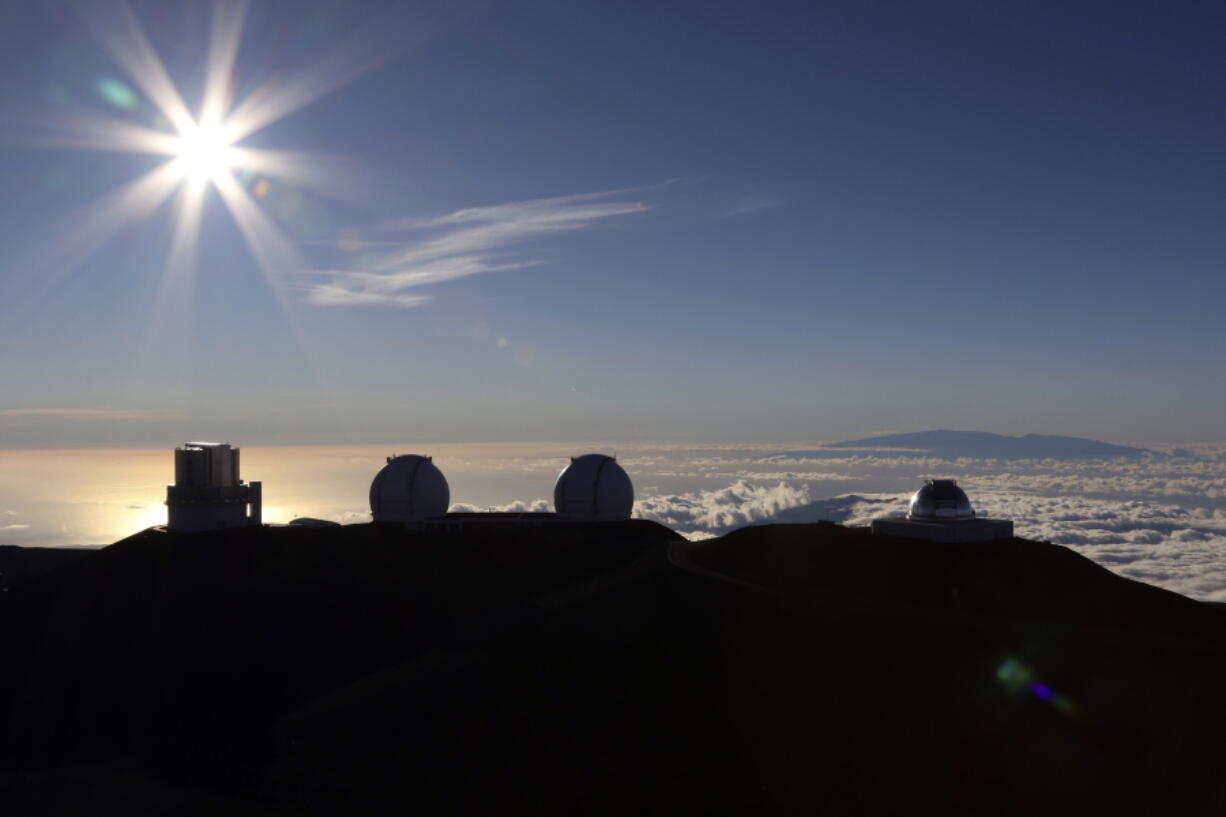 FILE - The sun sets behind telescopes on July 14, 2019, at the summit of the Big Island's Mauna Kea in Hawaii. For over 50 years, telescopes have dominated the summit of Mauna Kea, a place sacred to Native Hawaiians and one of the best places in the world to study the night sky. That's now changing with a new state law saying Mauna Kea must be protected for future generations and that science must be balanced with culture and the environment.