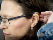 FILE - Kim M. Smith, leader of the Utah Deaf Hospital Rights movement and president of the Utah Association of the Deaf, brushes her hair away from her hearing aid as she poses for a portrait Monday, Jan. 20, 2020, at Alta View Hospital in Sandy, Utah.  Millions of Americans may be able to buy hearing aids without a prescription by this fall, under a long-awaited rule finalized Tuesday, Aug. 16, 2022, that's intended to make the devices more accessible to people with hearing problems. The Food and Drug Administration said the new regulation cuts red tape by creating a new class of hearing aids that don't require a medical exam, a prescription and other specialty services. Instead the devices will be sold online or over-the-counter at pharmacies and other retail stores.