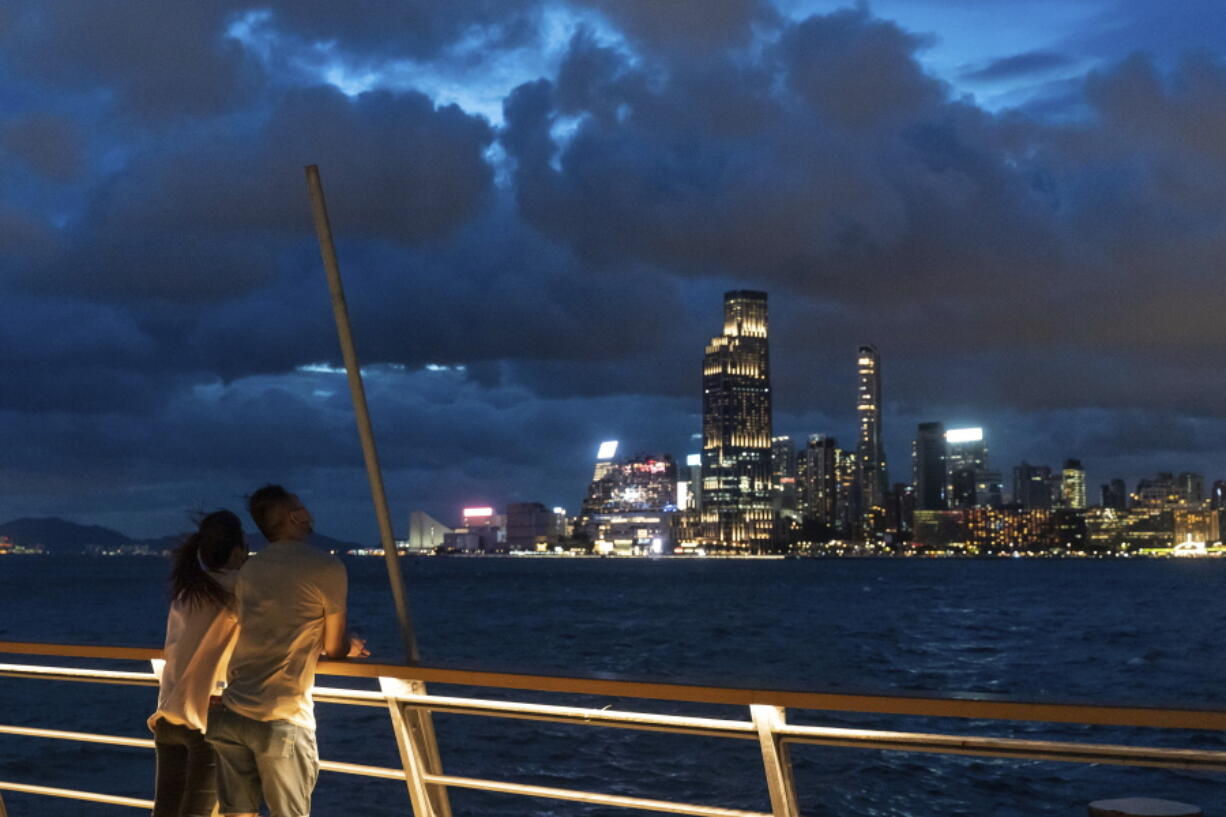 People stand at a railing overlooking Victoria Harbor as tropical cyclone Ma-on approaches Hong Kong, Wednesday, Aug. 24, 2022. Tropical Storm Ma-on was gaining strength as it headed for Hong Kong and other parts of southeastern China on Wednesday after displacing thousands in the Philippines.