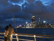 People stand at a railing overlooking Victoria Harbor as tropical cyclone Ma-on approaches Hong Kong, Wednesday, Aug. 24, 2022. Tropical Storm Ma-on was gaining strength as it headed for Hong Kong and other parts of southeastern China on Wednesday after displacing thousands in the Philippines.