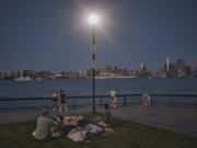 FILE - People spend time at the park at dusk during a summer heat wave, July 21, 2022, in Hoboken, N.J. The continental United States in July set a record for overnight warmth, providing little relief from the day's sizzling heat for people, animals, plants and the electric grid, meteorologists said.