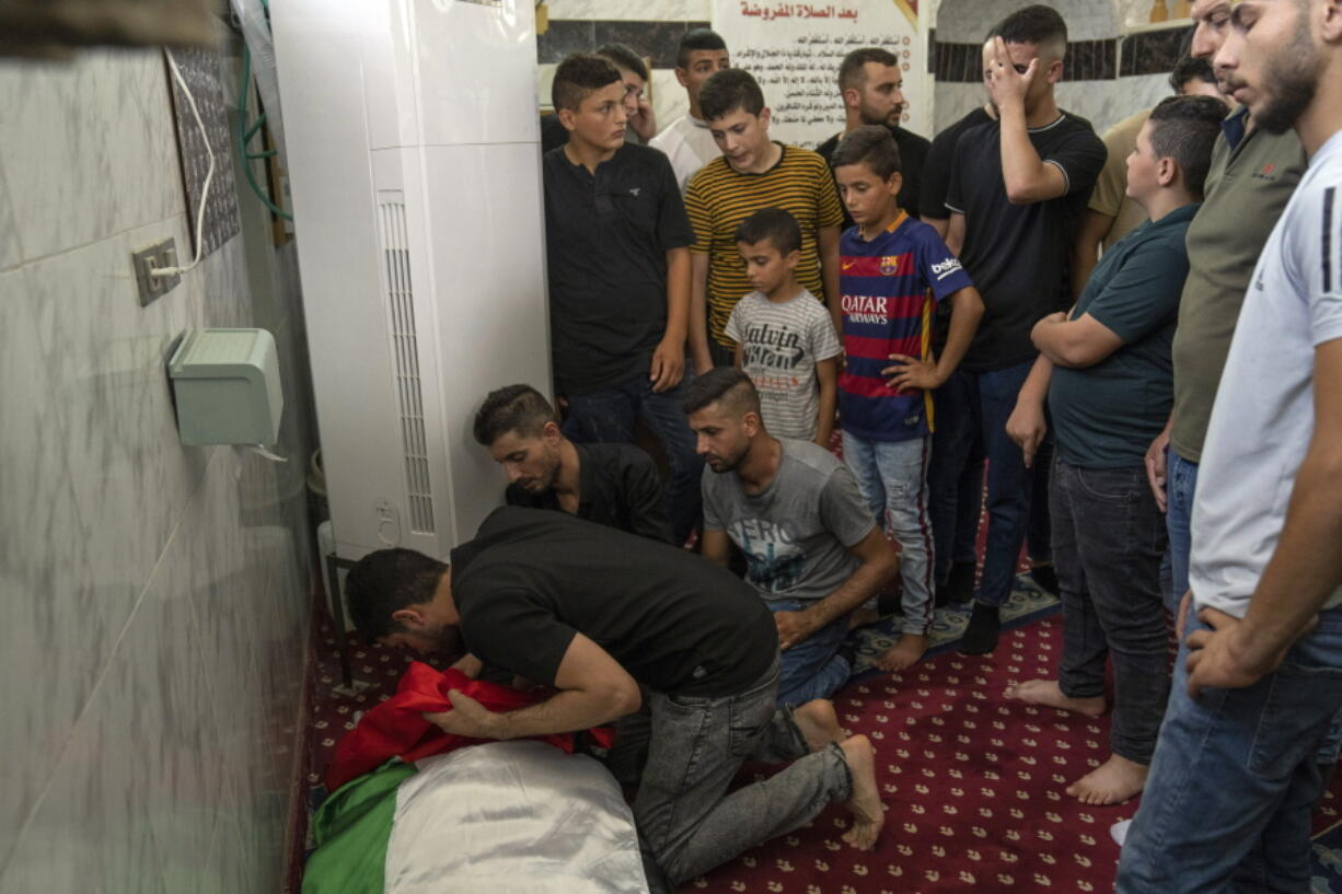 Mourners take a last look at the body of Palestinian Salah Sawafta, 58, who was shot and killed outside a bakery as he returned from dawn prayers earlier this month, during an early morning Israeli army arrest raid, at his funeral in a mosque, in the West Bank city of Tubas, Friday, Aug. 19, 2022. At least 85 Palestinians have been killed in the West Bank this year as Israeli forces have carried out nightly raids in cities, towns and villages, making it the deadliest in the occupied territory since 2016.