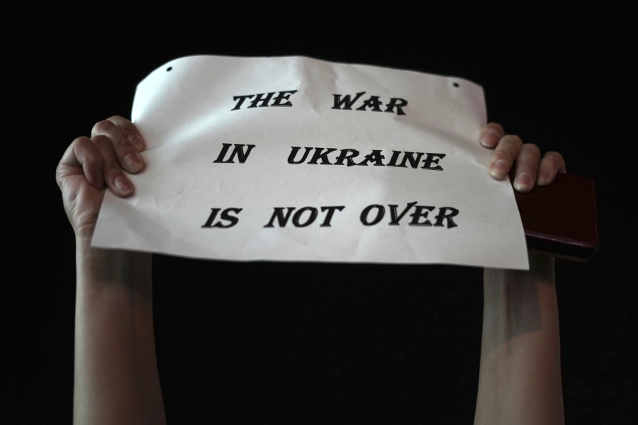 A person holds a placard that reads, "The war in Ukraine is not over," in Habima Square as people gather to mark Ukrainian Independence Day in Tel Aviv, Israel, Wednesday, Aug. 24, 2022.