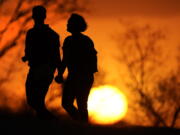 FILE - In this March 10, 2021 file photo, a couple walks through a park at sunset in Kansas City, Mo. U.S. life expectancy dropped for two consecutive years in 2020 and 2021, marking the first such trend since the early 1920s, according to a new government report.