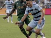Sporting Kansas City midfielder Roger Espinoza (15) and Portland Timbers midfielder Diego Char? (21) chase the ball during the first half of an MLS soccer match Sunday, Aug. 21, 2022, in Kansas City, Kan.