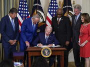 FILE - President Joe Biden signs the Democrats' landmark climate change and health care bill in the State Dining Room of the White House in Washington, Aug. 16, 2022, as from left, Sen. Joe Manchin, D-W.Va., Senate Majority Leader Chuck Schumer of N.Y., House Majority Whip Rep. James Clyburn, D-S.C., Rep. Frank Pallone, D-N.J., and Rep. Kathy Castor, D-Fla., watch. After decades of failed attempts, Democrats passed legislation that aims to reign in the soaring costs of drugs for some Americans.