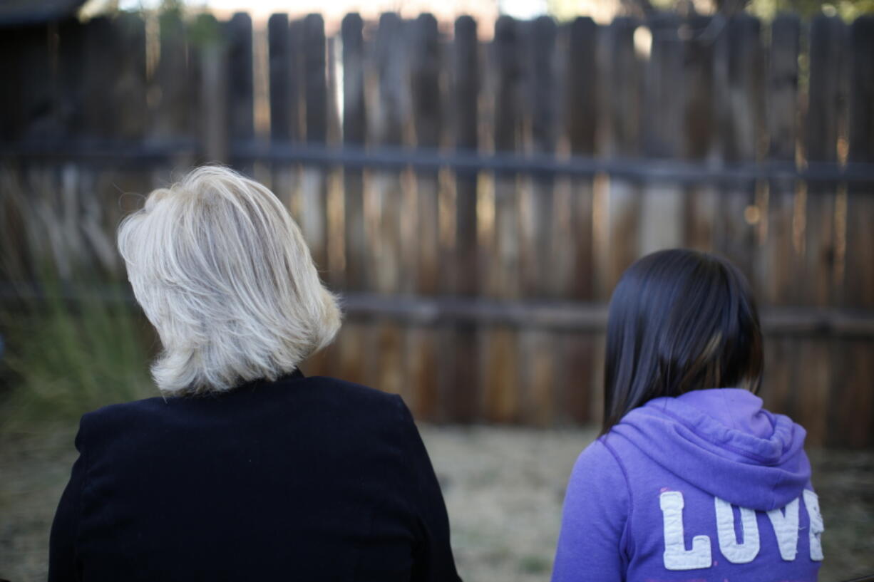 MJ and her adoptive mother sit for an interview with The Associated Press in Sierra Vista, Ariz., Oct. 27, 2021. State authorities placed MJ in foster care after learning that her father, the late Paul Adams, sexually assaulted her and posted video of the assaults on the Internet.