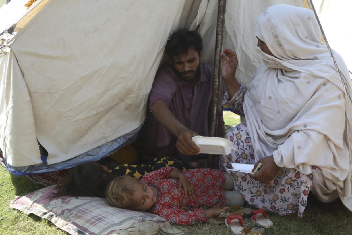 Rubina Bibi, 53, right, sit near to her family after take refuge at a camp after fleeing her flood-hit homes, in Charsadda, Pakistan, Tuesday, Aug. 30, 2022. Disaster officials say nearly a half million people in Pakistan are crowded into camps after losing their homes in widespread flooding caused by unprecedented monsoon rains in recent weeks.