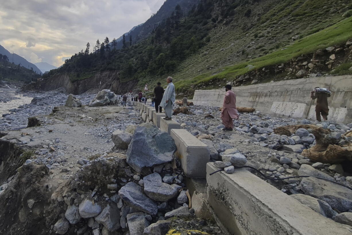 Local residents examine a portion of a road destroyed by floodwaters in the Kalam Valley in northern Pakistan, Tuesday, Aug. 30, 2022. Officials in Pakistan raised concerns Wednesday over the spread of waterborne diseases among thousands of flood victims as flood waters from powerful monsoon rains began to recede in many parts of the country.