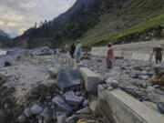 Local residents examine a portion of a road destroyed by floodwaters in the Kalam Valley in northern Pakistan, Tuesday, Aug. 30, 2022. Officials in Pakistan raised concerns Wednesday over the spread of waterborne diseases among thousands of flood victims as flood waters from powerful monsoon rains began to recede in many parts of the country.