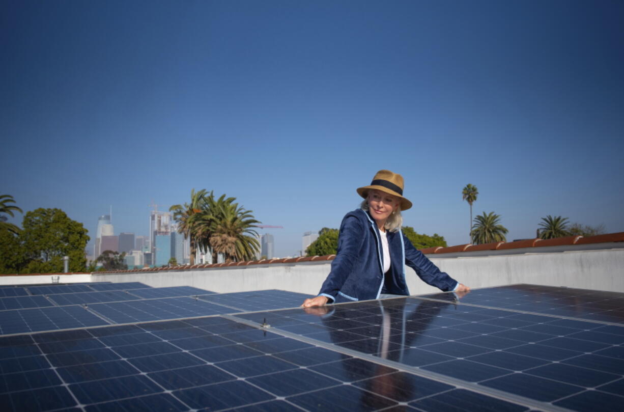 In this image provided by Ben Gibbs, Wendy Schmidt visits a community solar installation atop the roof of an Esperanza Community Housing apartment building, across the street from an oil drilling site in South Central Los Angeles on Nov. 3, 2021. The Schmidt Family Foundation funded the installation of the solar panels in 2017 so tenants could directly access renewable energy.