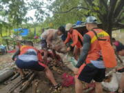 In this photo provided by the Philippine Coast Guard, rescuers carry vegetables as they move them to safer grounds in Tuguegarao, Cagayan province, northern Philippines on Tuesday Aug. 23, 2022. A tropical storm lashed the northern Philippines with strong wind and rain Tuesday, injuring at least two people and prompting the president to close schools and government offices in the capital and outlying provinces.