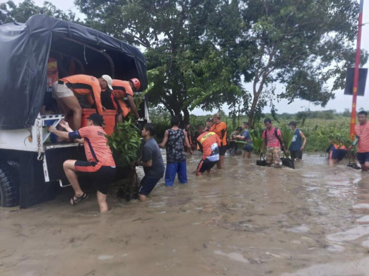 In this handout photo provided by the Philippine Coast Guard, rescuers help residents move to safer grounds in Tuguegarao, Cagayan province, northern Philippines on Tuesday Aug. 23, 2022. A tropical storm lashed the northern Philippines with strong wind and rain Tuesday, injuring at least two people and prompting the president to close schools and government offices in the capital and outlying provinces.