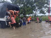 In this handout photo provided by the Philippine Coast Guard, rescuers help residents move to safer grounds in Tuguegarao, Cagayan province, northern Philippines on Tuesday Aug. 23, 2022. A tropical storm lashed the northern Philippines with strong wind and rain Tuesday, injuring at least two people and prompting the president to close schools and government offices in the capital and outlying provinces.