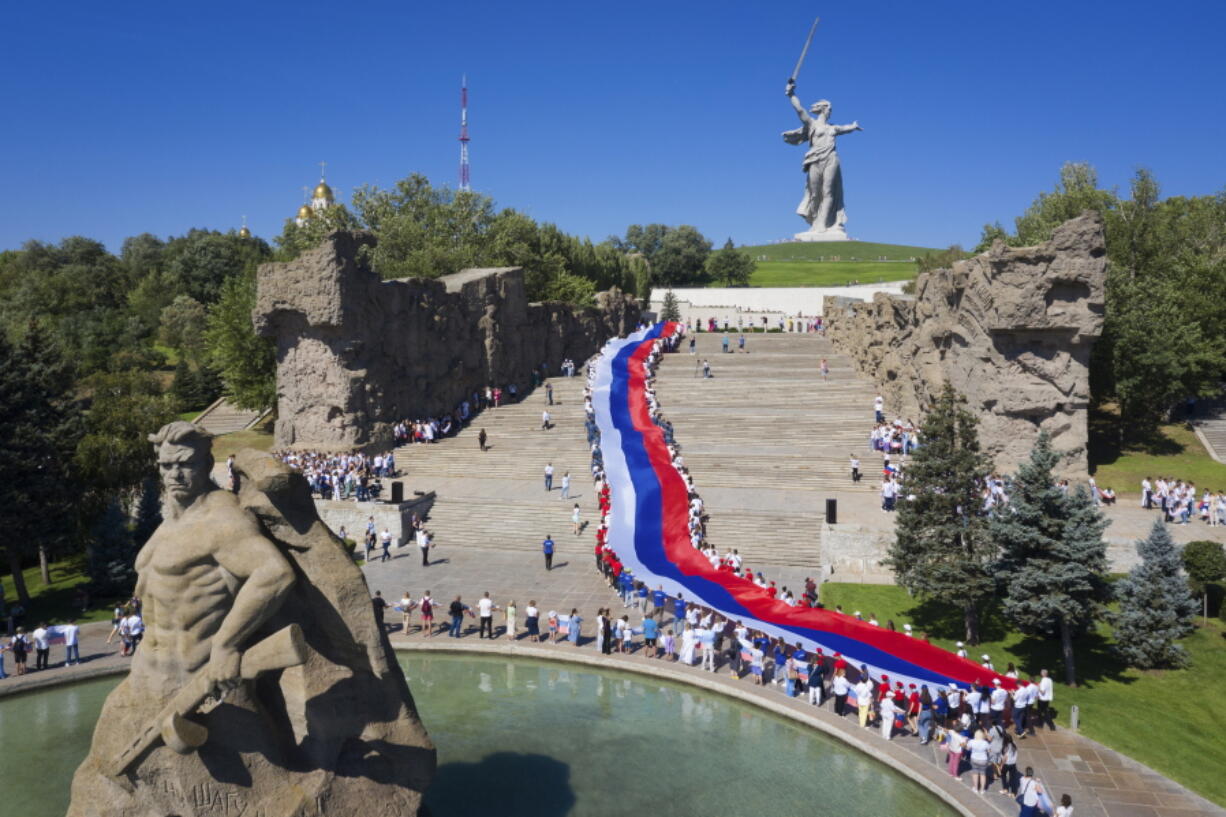 People carry a giant Russian flag during celebration of the Day of The National Flag in Mamayev Kurgan, the World War II Battle of Stalingrad memorial, in Volgograd, Russia, Monday, Aug. 22, 2022.