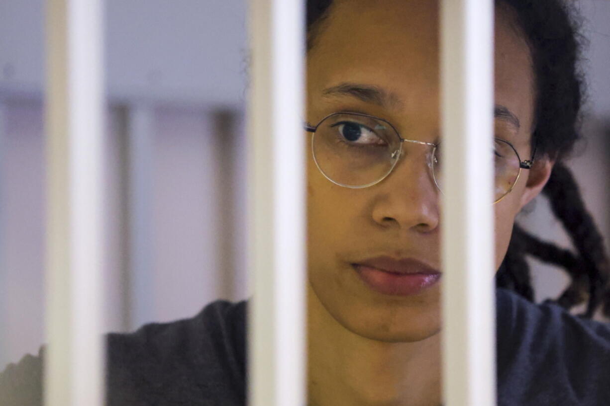 FILE - US Basketball player Brittney Griner looks through bars as she listens to the verdict standing in a cage in a courtroom in Khimki, outside Moscow, Russia, Thursday, Aug. 4, 2022. Lawyers for American basketball star Brittney Griner on Monday, Aug. 15, 2022 filed an appeal of her nine-year Russian prison sentence for drugs possession. Griner, a center for the Phoenix Mercury and a two-time Olympic gold medalist, was convicted on Aug. 4. She was arrested in February at Moscow's Sheremetyevo Airport after vape canisters containing cannabis oil were found in her luggage.