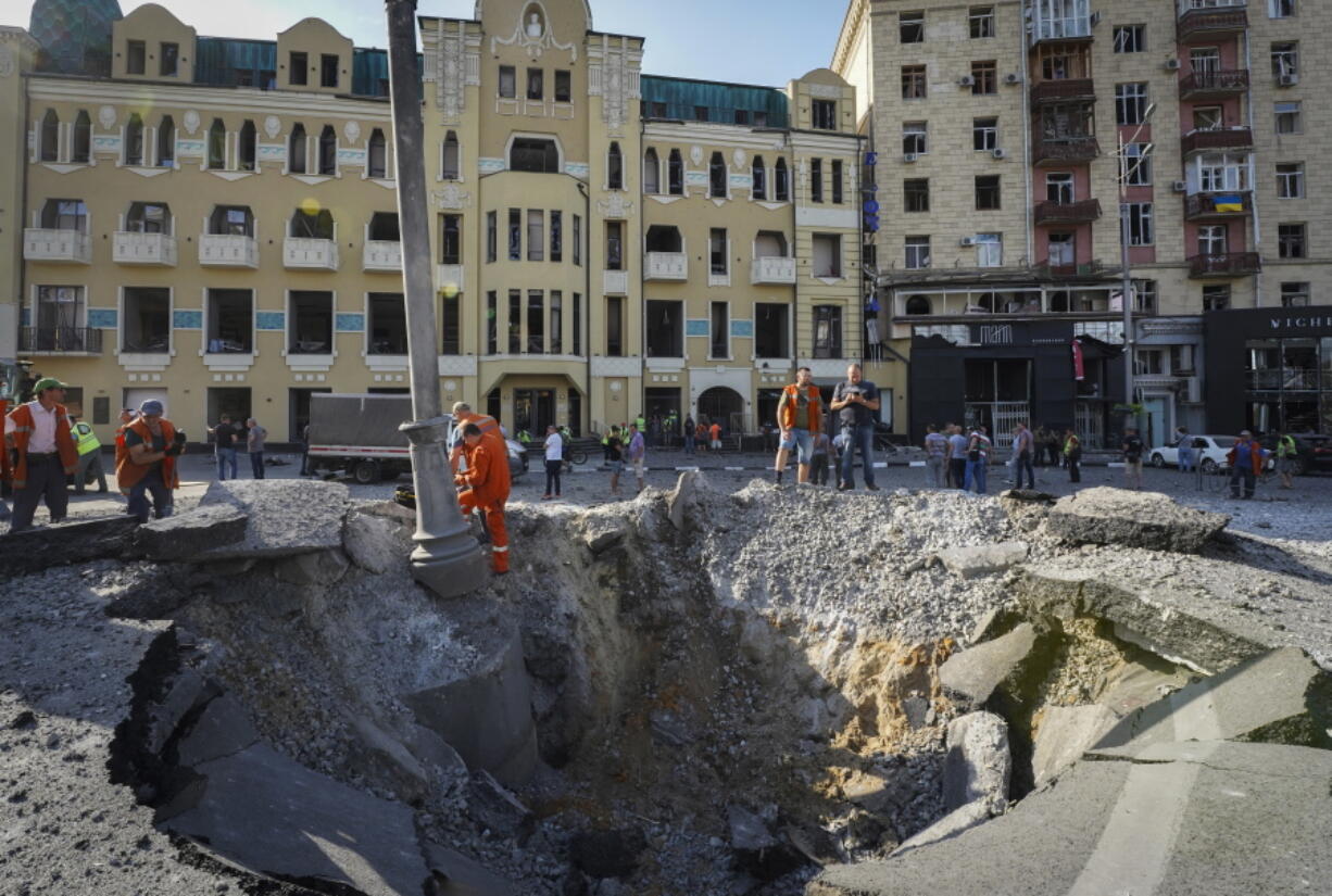 A view of a crater from a night Russian rocket attack, near to damaged buildings in downtown Kharkiv, Ukraine, Saturday, Aug. 27, 2022.