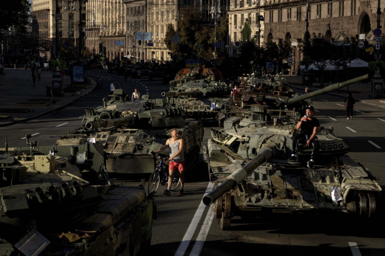 People walk around destroyed Russian military vehicles installed in downtown Kyiv, Ukraine, Wednesday, Aug. 24, 2022. Kyiv authorities have banned mass gatherings in the capital through Thursday for fear of Russian missile attacks. Independence Day, like the six-month mark in the war, falls on Wednesday.