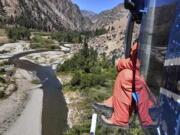 FILE - This photo provided by the Idaho Department of Fish and Game shows fisheries biologist Eli Felts looking down at Loon Creek to count chinook salmon spawning beds in the Frank Church River of No Return Wilderness, Idaho, on Sept. 9, 2020. A five-year review by U.S. officials has determined that Endangered Species Act protections for ocean-going salmon and steelhead that reproduce in the Snake River and its tributaries in Idaho must remain in place.