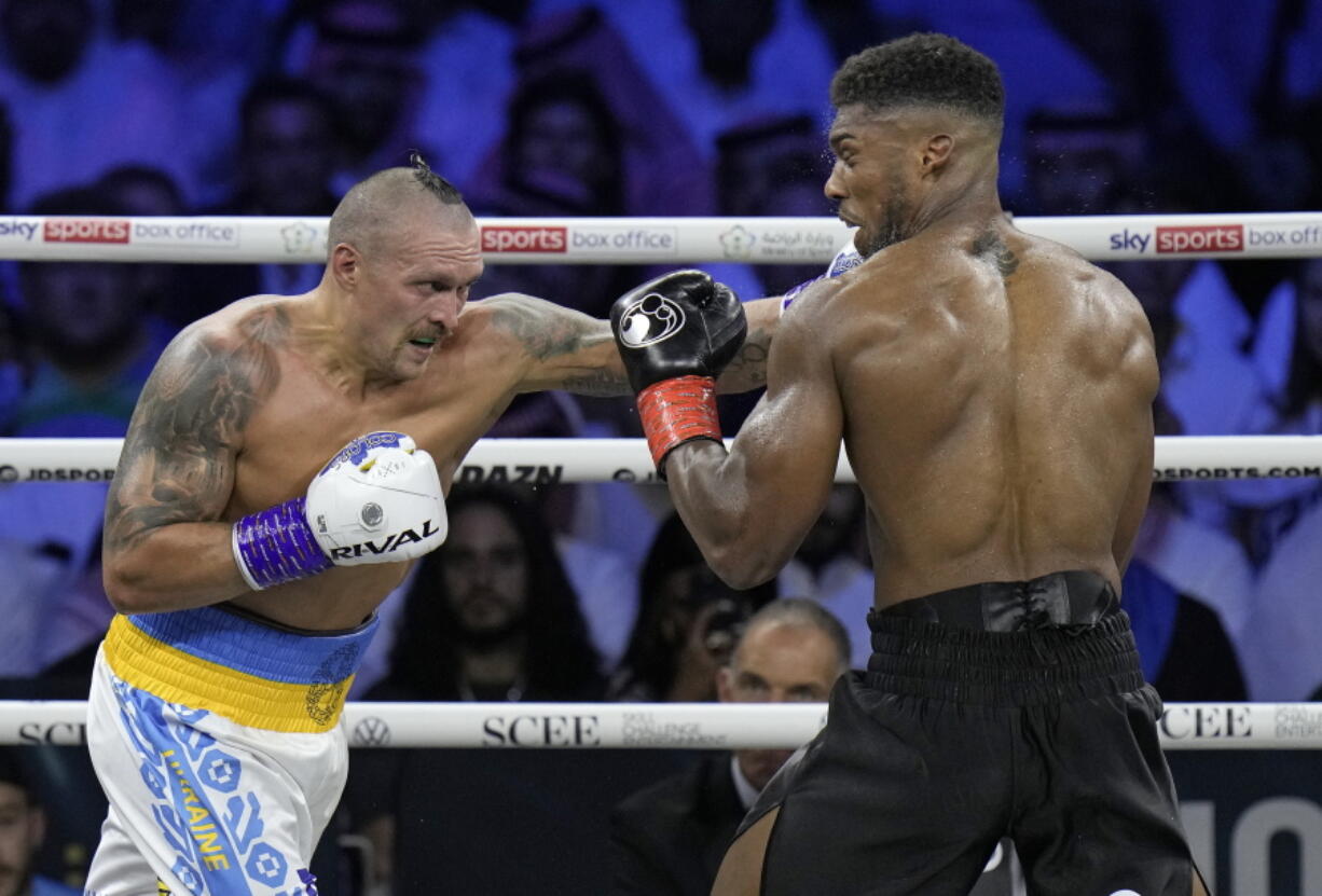 Britain's Anthony Joshua, right, takes a blow from Ukraine's Oleksandr Usyk during their world heavyweight title fight at King Abdullah Sports City in Jeddah, Saudi Arabia, Sunday, Aug. 21, 2022.