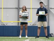 Becca Erenbaum, left, a senior football research analyst, and Peter Engler, a football research assistant, hold laptop computers as they pose for a photo on Aug. 3, 2022 at the Seattle Seahawks' NFL football indoor training facility in Renton, Wash. Coming off their worst season in head coach Pete Carroll's tenure, the Seahawks aimed to supplement their analytics staff -- that before this season was on the smaller side compared to other NFL teams -- with the hiring of Erenbaum and Engler, who will be called upon to take various data streams data and create a statistical analysis of situations. (AP Photo/Ted S. Warren) (Ted S.