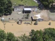 in this aerial photo, some homes in Breathitt County, Ky., are still surrounded by water on Saturday, July 30, 2022, after historic rains flooded many areas of Eastern Kentucky killing multiple people. A thin film of mud from the retreating waters covers many cars and homes.