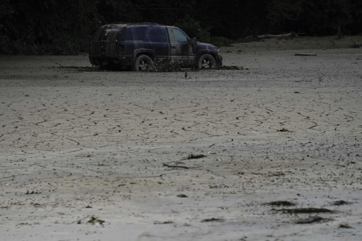 A vehicle is abandoned and surrounded by mud caused by massive flooding on Friday, Aug. 5, 2022, near Haddix, Ky.