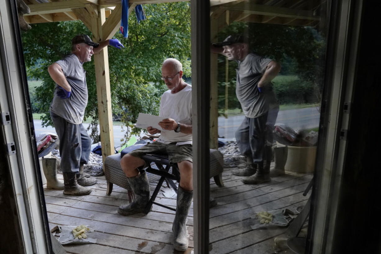 Paul Sparkman, left, and Danny Laferty, stand next to damaged debris on Laferty's front porch on Tuesday, Aug. 2, 2022, in Hindman, Ky., as they clean up debris from massive flooding.