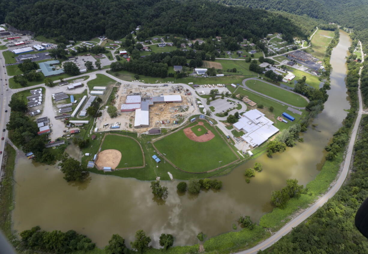 In this aerial image, the river is still high around the homes in Breathitt County, Ky., on Saturday, July 30, 2022. Recovery has begun in many of the narrow hollers after historic rains flooded many areas of Eastern Kentucky killing more at least two dozen people. A layer of mud from the retreating waters covers many cars and homes.