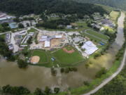 In this aerial image, the river is still high around the homes in Breathitt County, Ky., on Saturday, July 30, 2022. Recovery has begun in many of the narrow hollers after historic rains flooded many areas of Eastern Kentucky killing more at least two dozen people. A layer of mud from the retreating waters covers many cars and homes.