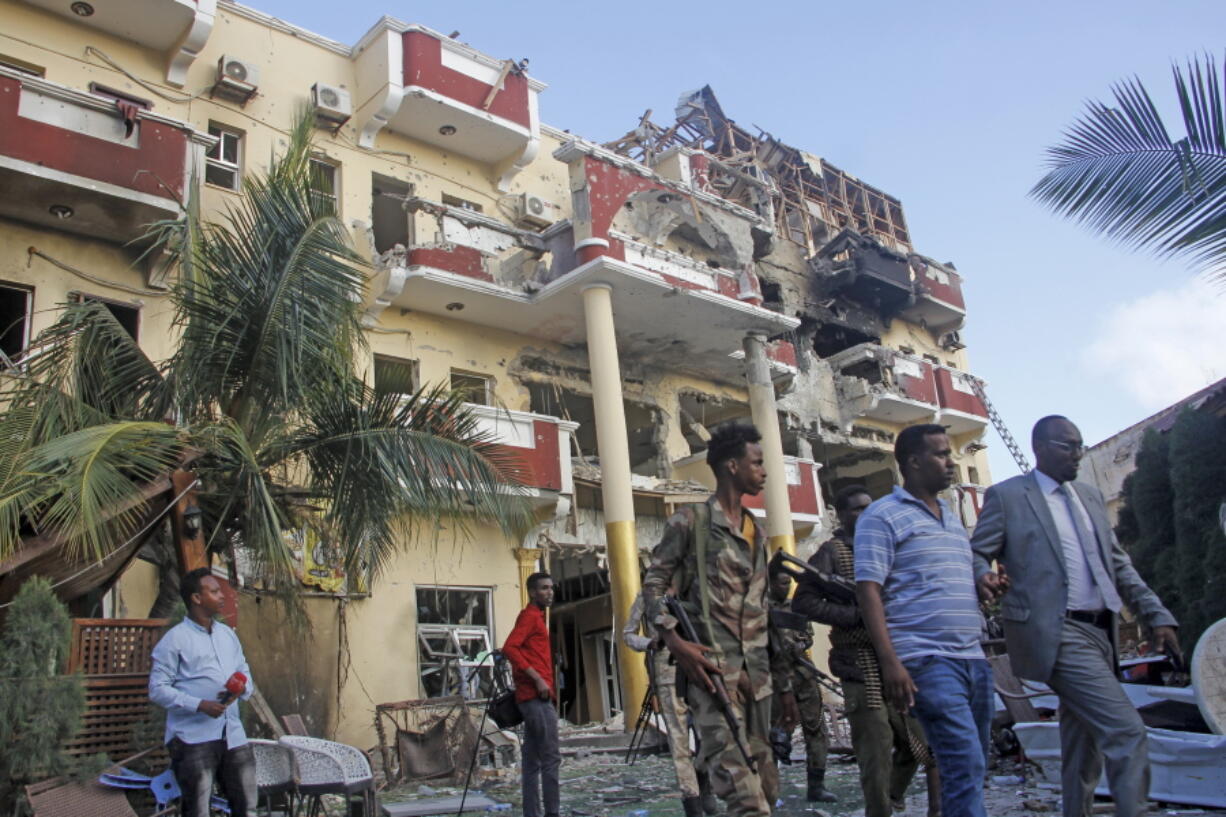 Security forces and others walk in front of the damaged Hayat Hotel in the capital Mogadishu, Somalia Sunday, Aug. 21, 2022. Somali authorities on Sunday ended a deadly attack in which at least 20 people were killed and many others wounded when gunmen from the Islamic extremist group al-Shabab, which has ties with al-Qaida, stormed the Hayat Hotel in the capital on Friday evening.