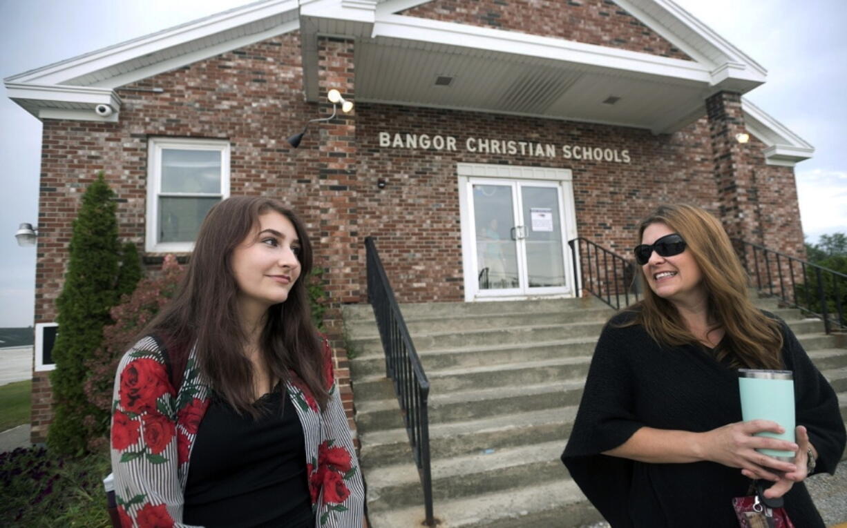 Former Bangor Christian Schools sophomore Olivia Carson, then 15, of Glenburn, Maine, left, stands with her mother Amy while getting dropped off on the first day of school on August 28, 2018 in Bangor, Maine. Parents of students enrolled in religious schools fought for years -- all the way to the Supreme Court -- for tuition to be reimbursed by the state, the same as other private schools. But only one religious school has signed up to participate so far.