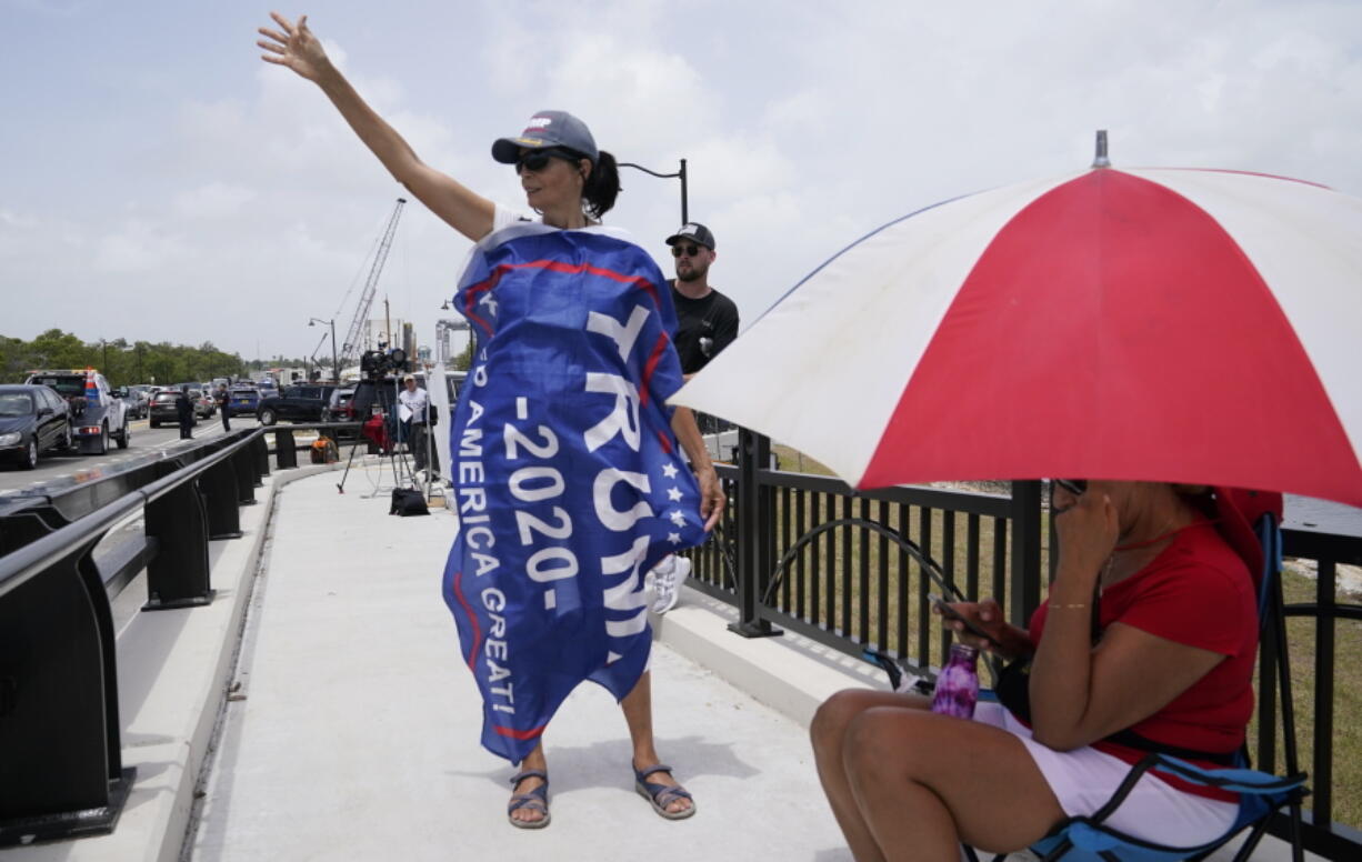 A Donald Trump supporter stands on a bridge outside the entrance to former President Donald Trump's Mar-a-Lago estate, Tuesday, Aug. 9, 2022, in Palm Beach, Fla. The FBI searched Trump's Mar-a-Lago estate as part of an investigation into whether he took classified records from the White House to his Florida residence, people familiar with the matter said Monday.