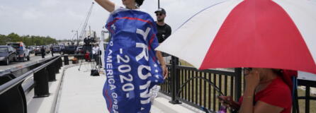 A Donald Trump supporter stands on a bridge outside the entrance to former President Donald Trump's Mar-a-Lago estate, Tuesday, Aug. 9, 2022, in Palm Beach, Fla. The FBI searched Trump's Mar-a-Lago estate as part of an investigation into whether he took classified records from the White House to his Florida residence, people familiar with the matter said Monday.