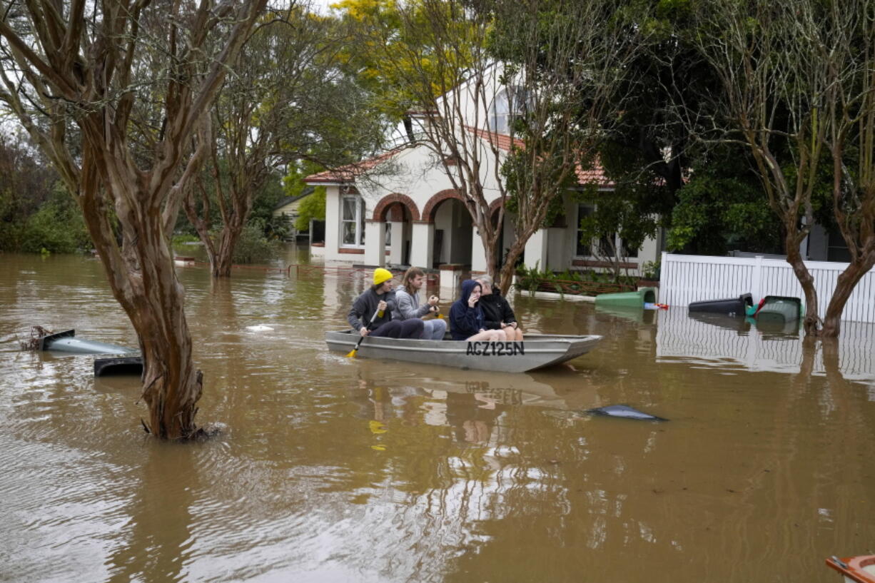 FILE - People paddle through a flooded street at Windsor on the outskirts of Sydney, Australia, July 5, 2022. The U.N. weather agency is predicting the phenomenon known as La Nina is poised to last through the end of this year, a mysterious "triple dip" -- the first this century -- caused by three straight years of its effect on climate patterns like drought and flooding worldwide.