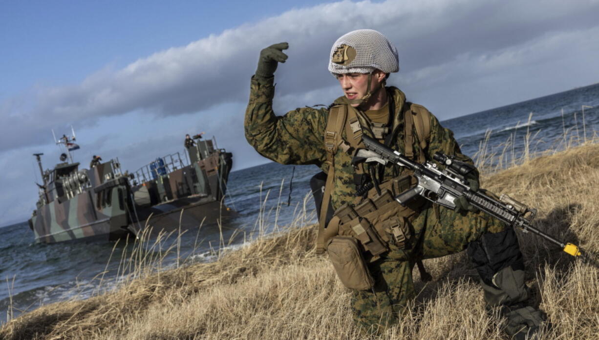 In this image provided by the North Atlantic Treaty Organization, a U.S. marine waves his troops onward after using Dutch landing craft to land near Sandstrand, Norway, March 21, 2022, during the Exercise Cold Response 22.