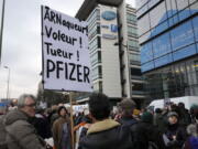 FILE - A demonstrator holds a placard reading "Scammer, thief, killer, Pfizer" during a protest against the vaccine pass and vaccinations to protect against COVID-19 in front of the Pfizer headquarters, in Paris, on Jan. 29, 2022. An anti-vaccine group that has harassed doctors and public officials in Italy and France is still active on platforms like Facebook despite efforts to rein in their abuse and misinformation. The organization, known as V--V, bombards its victims with dozens, hundreds or even thousands of abusive posts.