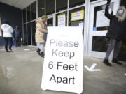 FILE - A sign asks those getting vaccinated to keep 6 feet apart during the vaccination event, Wednesday, Jan. 27, 2021, at Nevada Union High School in Grass Valley, Calif. The CDC has again revised its COVID guidelines, further relaxing quarantine recommendations and dropping the recommendation that people stay at least 6 feet away from each other.