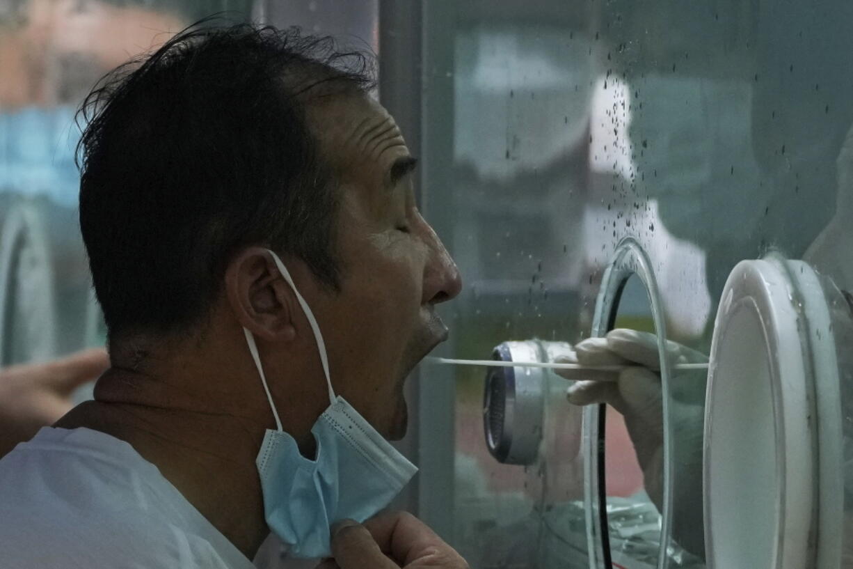 A man pulls his mask to get his routine COVID-19 throat swab at a coronavirus testing site in Beijing, Tuesday, Aug. 9, 2022. Chinese authorities have closed Tibet's famed Potala Palace after a minor outbreak of COVID-19 was reported in the Himalayan region.